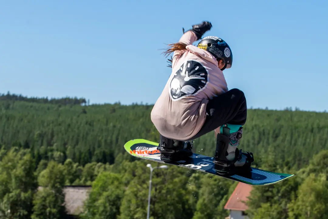 EN tjej hoppar med snowboard i kläppen arena