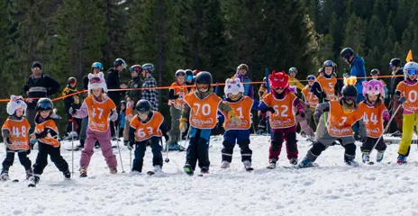 A crowd of children with race bibs on skis who have just started in our popular Easter competition, Chinese Easter Downhill.