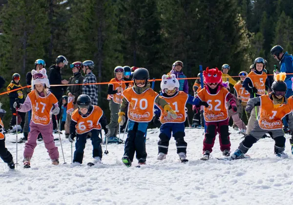 A crowd of children with race bibs on skis who have just started in our popular Easter competition, Chinese Easter Downhill.
