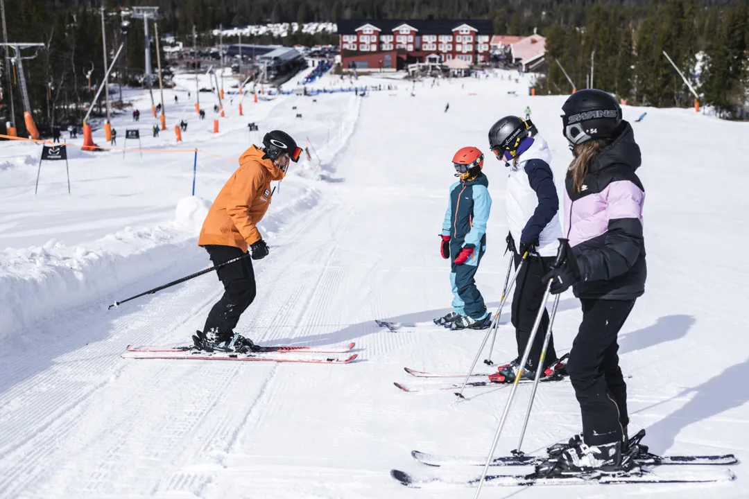 En skidlärare står och ger instruktioner till sin grupp i skidbacken