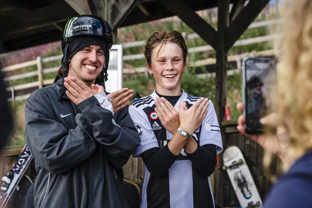 Två killar ler mot en mobilkamera när en kvinna fotar