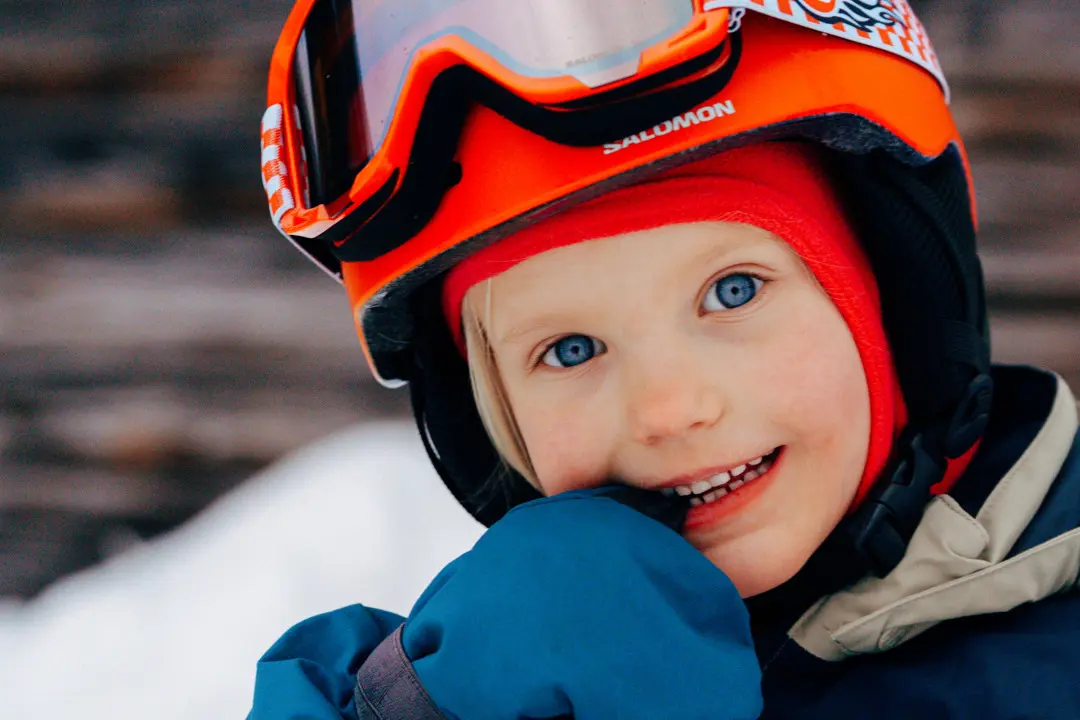 En flicka biter på handskarna och tittar in mot kameran