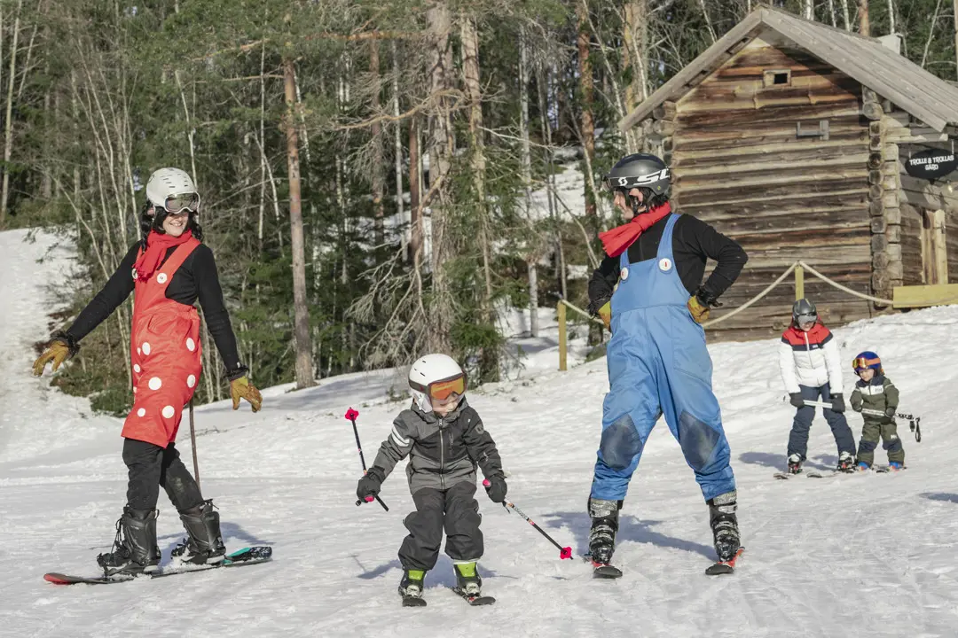 Trolle & Trolla are skiing together with the children. They have just passed Trollsterhusen, which can be seen in the background.