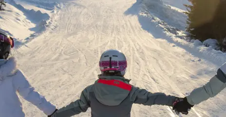 Three skiing girls hold each other's hands as they ski down Lämmeltåget