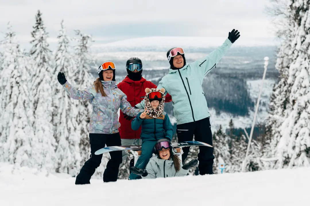 Hela familjen Eriksson står i backen och ler mot kameran