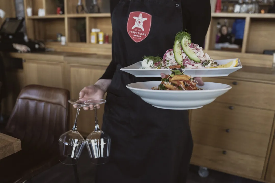 Servitris serverar två tallrikar med pasta