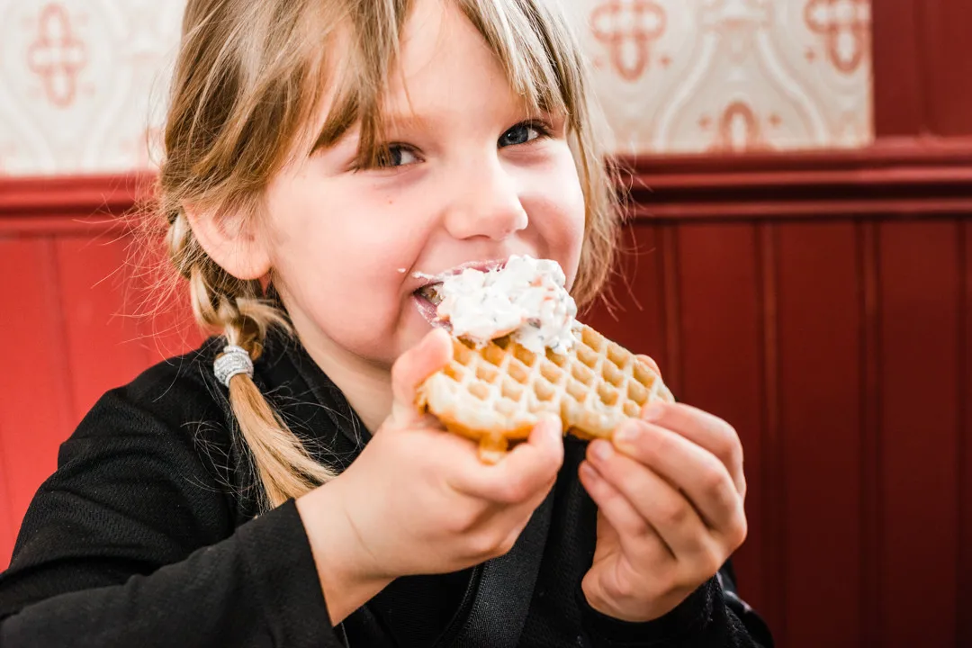 A girl is eating a waffle