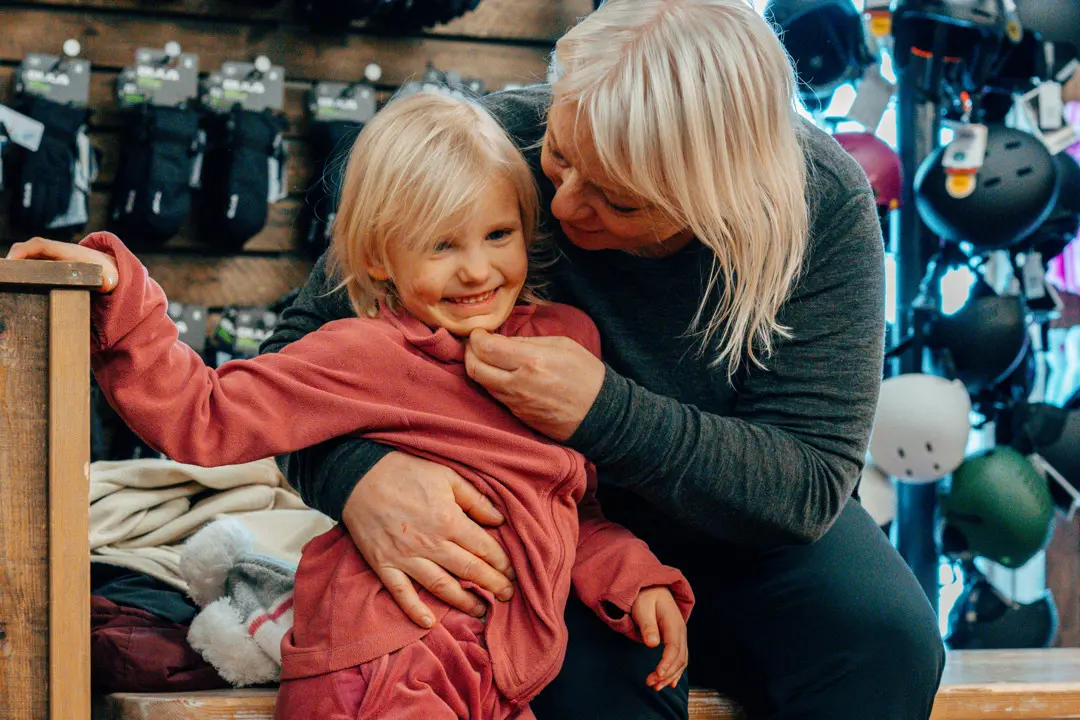 En mamma kramar om sin dotter inne på skidhyran