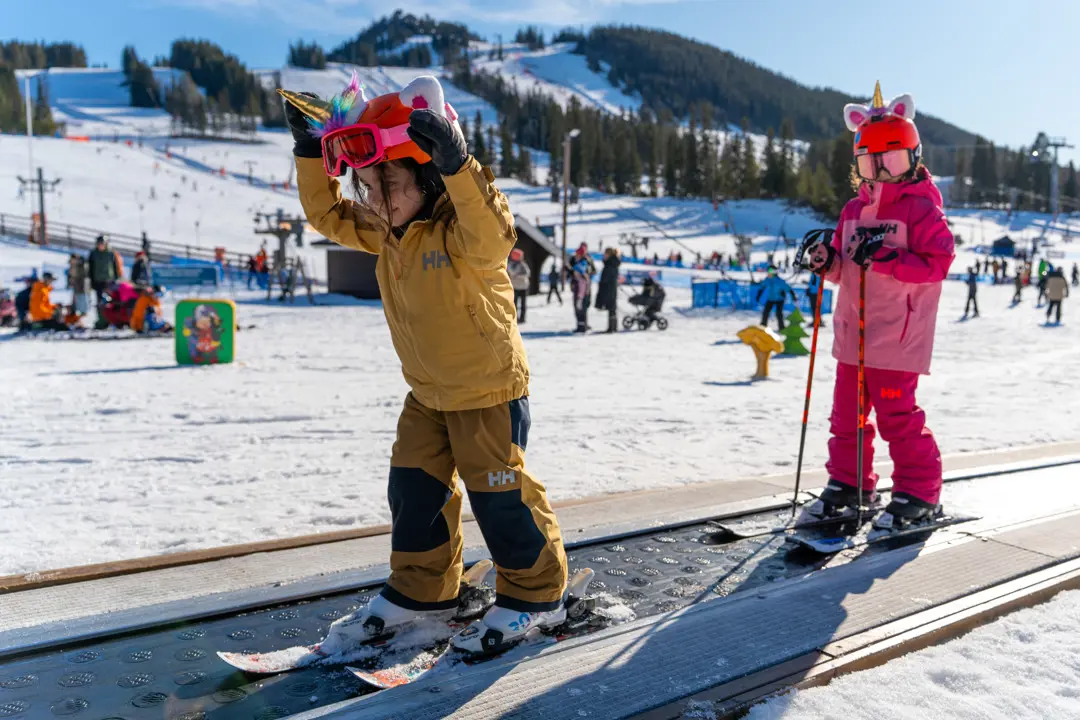 Two children riding the conveyor belt in the children's area