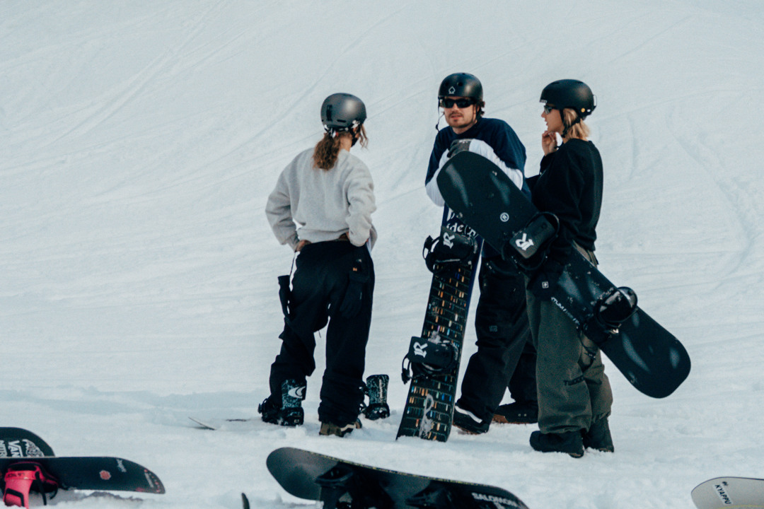 tre snowboardåkare står och pratar i parken