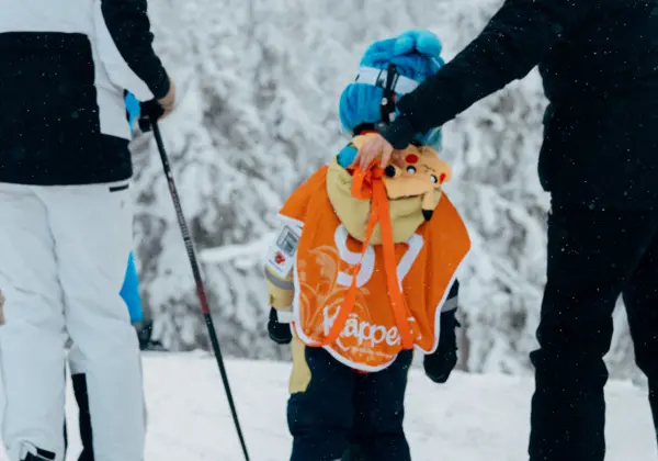 Three skiing girls hold each other's hands as they ski down Lämmeltåget
